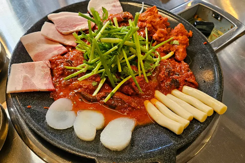 만석동 철판집의 쭈꾸미와 삼겹살, 떡, 스지가 함께 있는 철판 요리