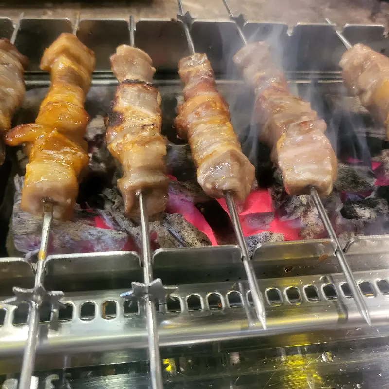 숯불 위에서 노릇하게 익어가는 양꼬치의 모습