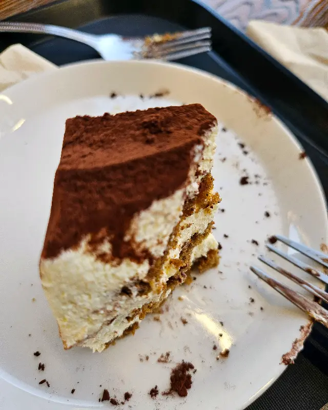 접시 위에 놓인 티라미수 케이크. 케이크는 촉촉하고 부드러워 보인다.