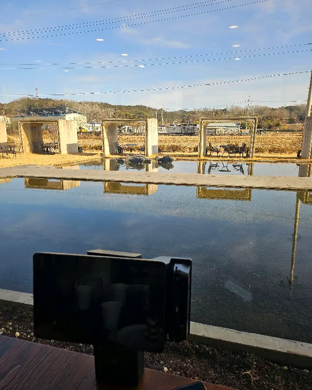 테이블에 놓인 휴대폰과 함께 보이는 논의 풍경. 일상 속에서 자연을 느낄 수 있다.