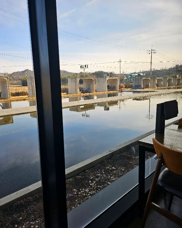 창밖으로 보이는 논의 풍경. 잔잔한 물결과 푸른 하늘이 평화로운 분위기를 자아낸다.