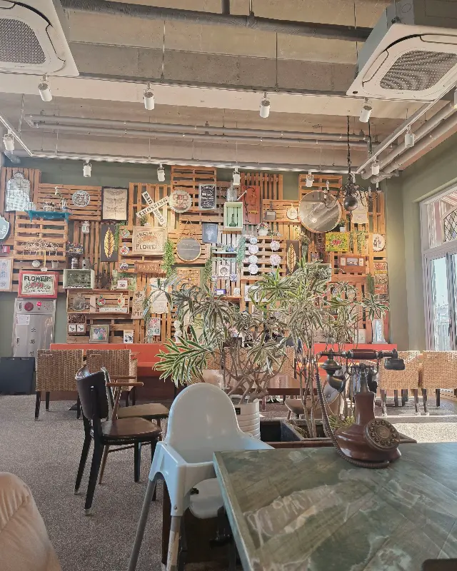 카페 내부의 테이블과 의자, 벽면 장식이 보이는 사진