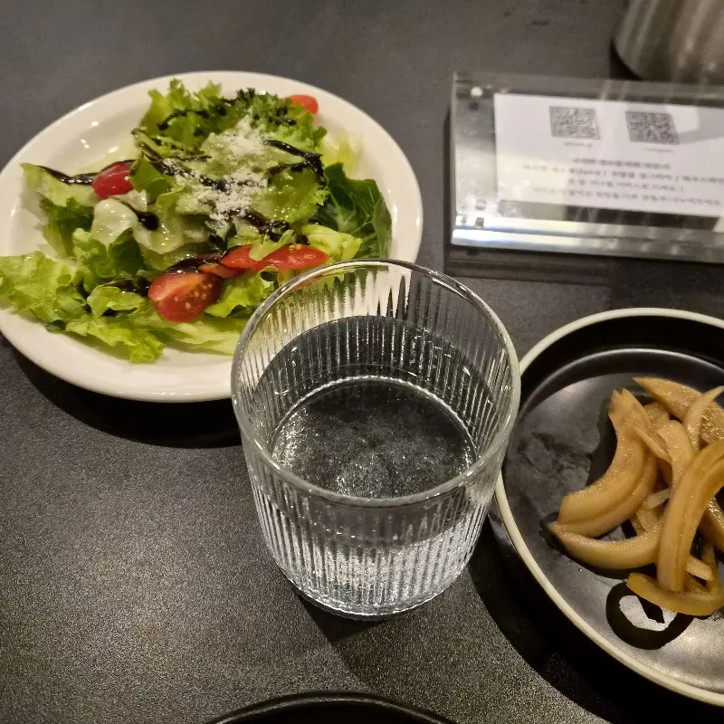 테이블 위에 놓인 샐러드, 물 컵, 그리고 양파 절임