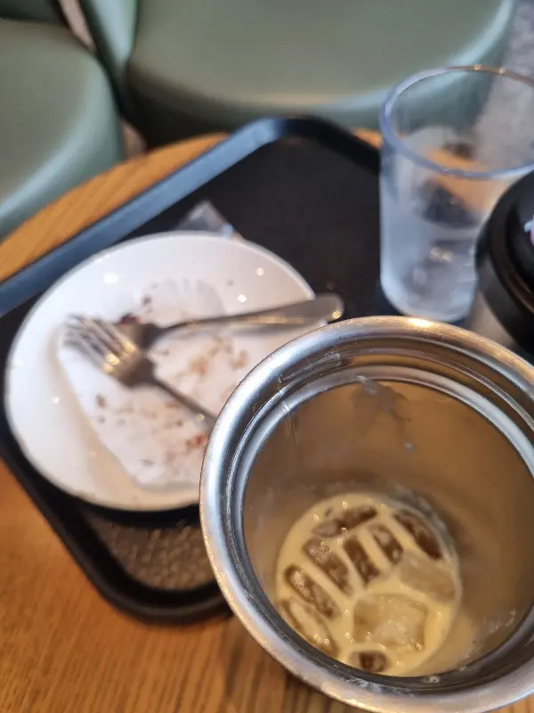 케이크를 다 먹은 접시와 커피가 담긴 텀블러