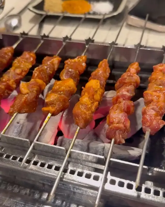 숯불 위에서 익어가는 양념 양꼬치의 클로즈업 샷