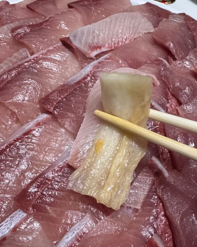 젓가락으로 집어 올린 방어회, 신선함이 느껴지는 투명한 붉은 빛깔