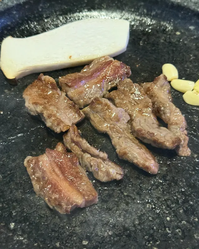 잘 구워진 고기와 함께 놓인 구운 마늘