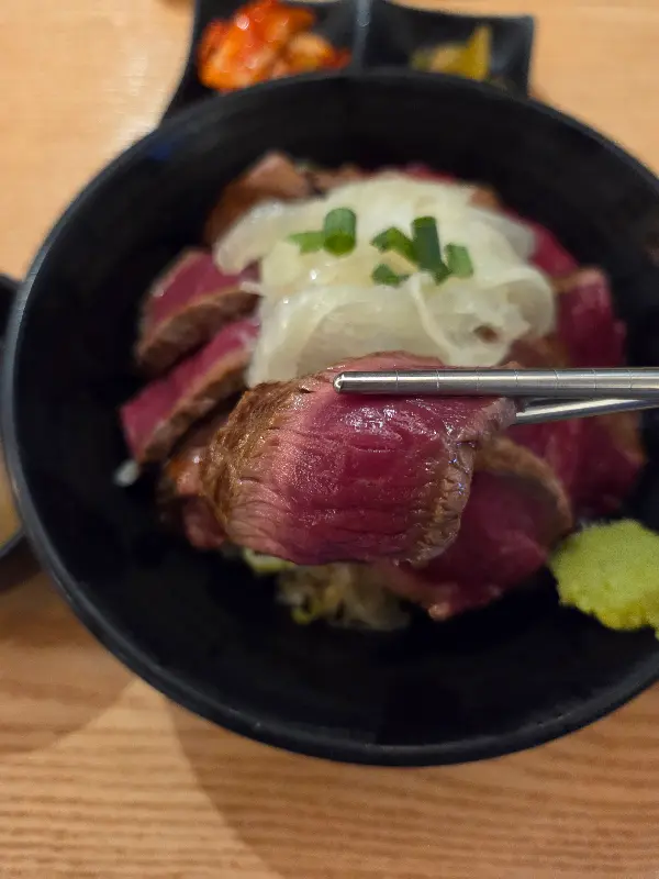 젓가락으로 스테이크 한 점을 들어 올리는 모습