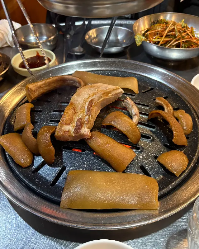 노릇하게 익어가는 삼겹살과 돼지 꼬리