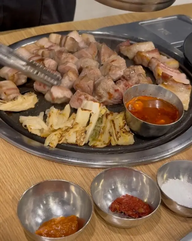 불판 위에 놓인 흑돼지, 멜젓, 묵은지의 조화