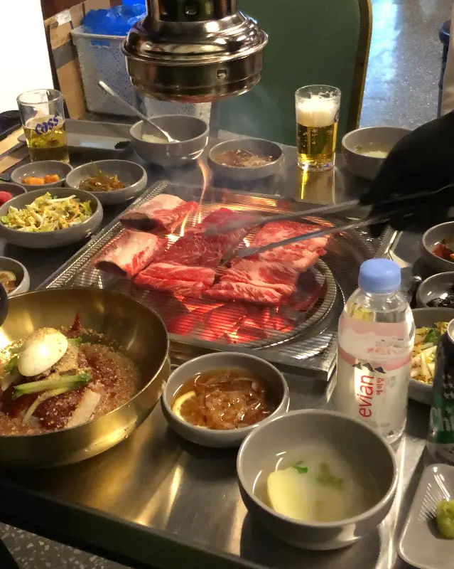 숯불 위에서 익어가는 고기와 주변 반찬들