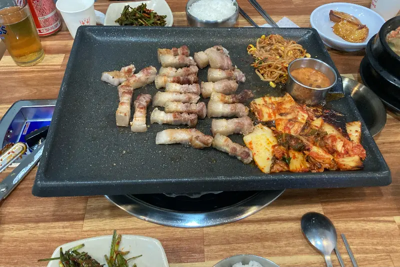 불판 위에 가지런히 놓인 흑돼지 오겹살