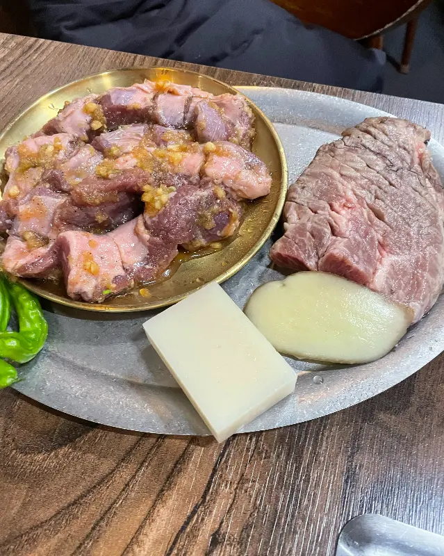 양념 갈매기살과 큼지막한 목살, 떡, 버섯 등이 한 접시에 담겨 나오는 모습