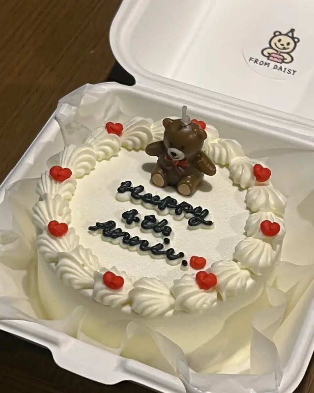 곰돌이 장식과 하트 초콜릿으로 장식된 4주년 기념 레터링 케이크