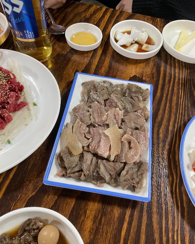 테이블 위에 수육, 육회, 곰탕 등이 놓여 있는 모습