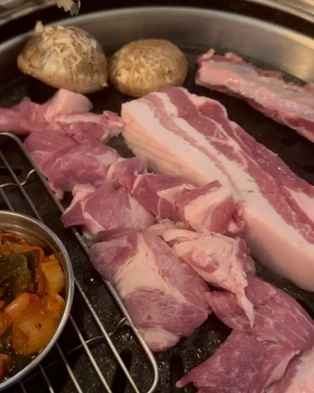 불판 위에서 익어가는 삼겹살과 버섯