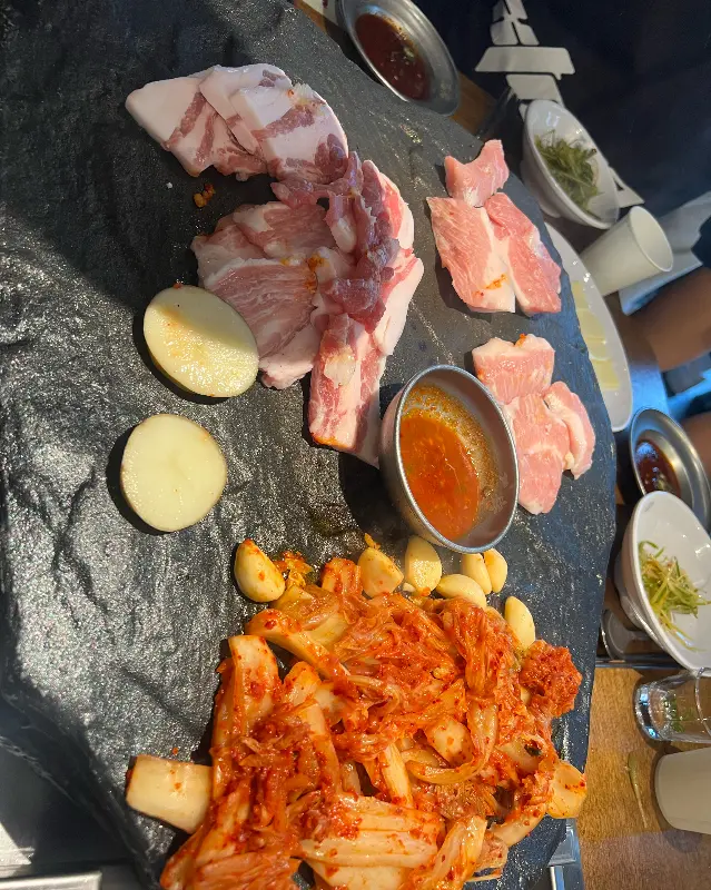 돌판 위에 구워진 삼겹살과 김치의 모습