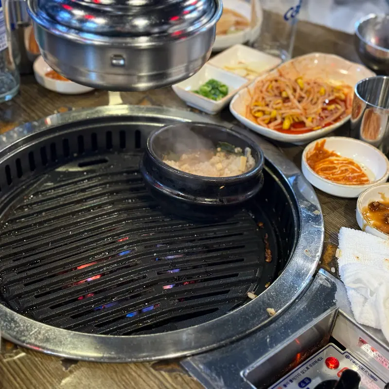 불판에 올려진 뚝배기와 다양한 반찬들