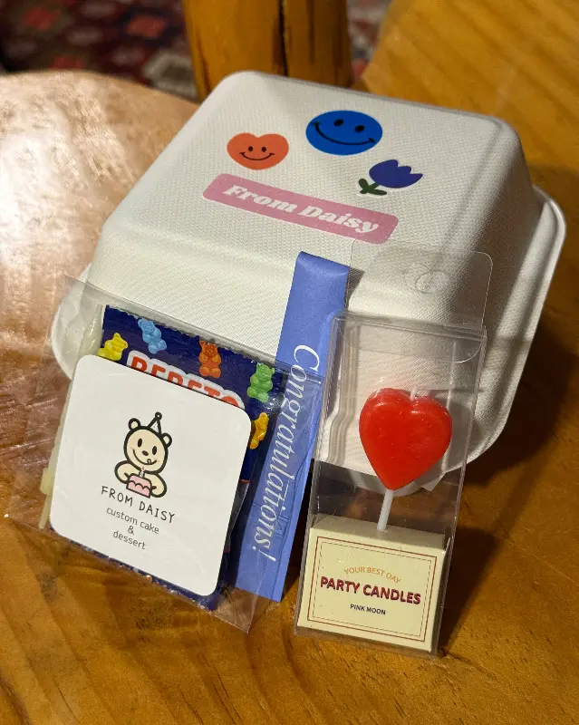 케이크 상자에 담겨있는 4주년 기념 케이크와 파티 용품