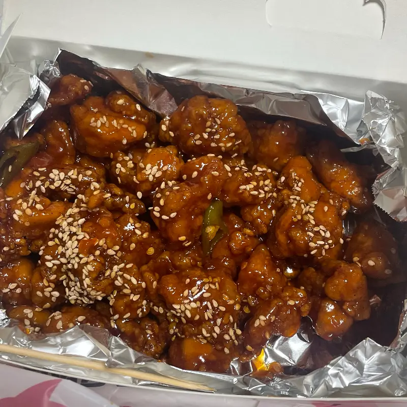 윤기가 흐르는 닭강정 위에 깨가 듬뿍 뿌려져 있는 모습