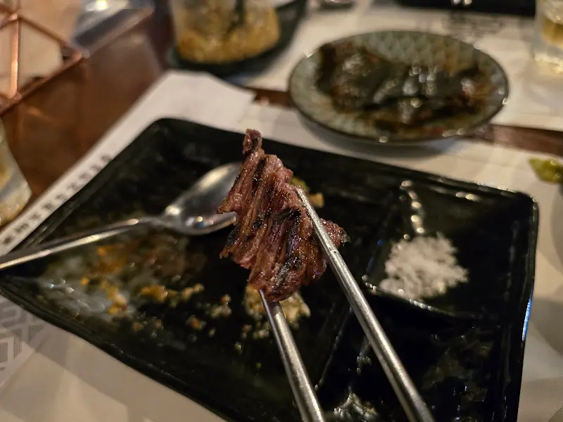 잘 구워진 한우 한 점을 젓가락으로 집어 올린 모습