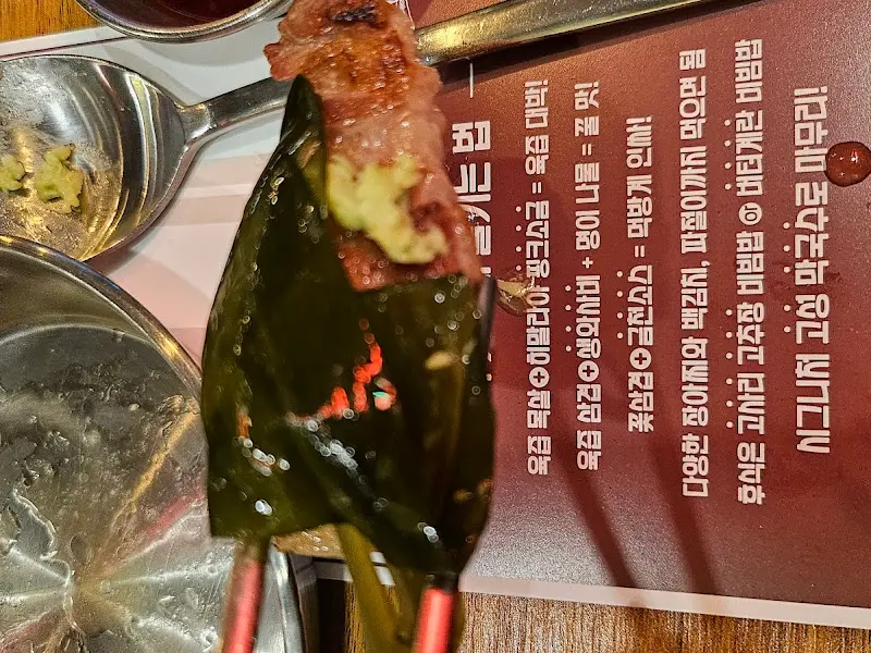 깻잎에 고기를 싸서 젓가락으로 집어 올린 모습