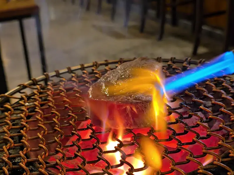 토치로 고기 겉면을 익히는 모습