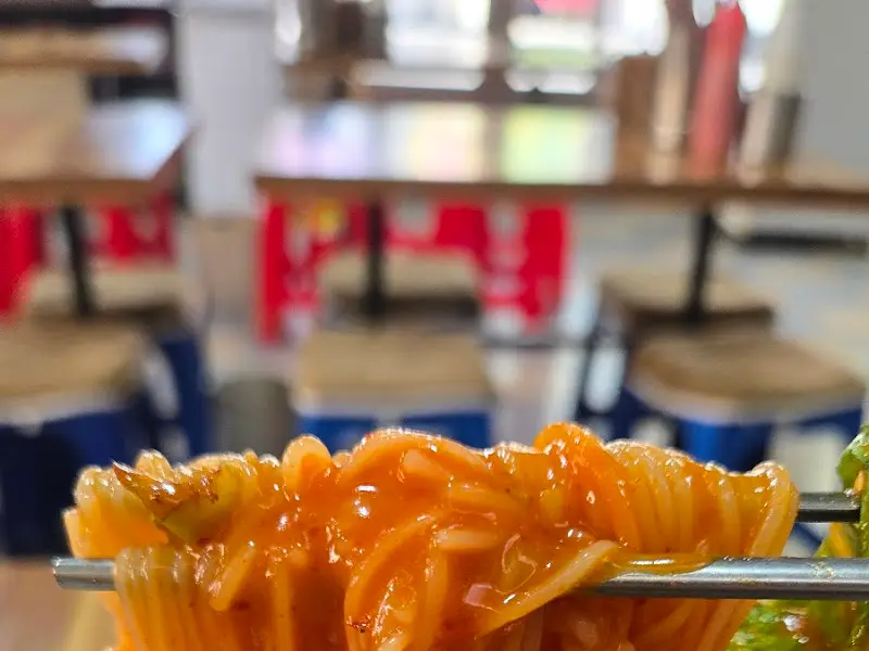 젓가락으로 비빔국수를 집어 올린 모습. 면발이 탱글탱글하고 윤기가 흐른다.