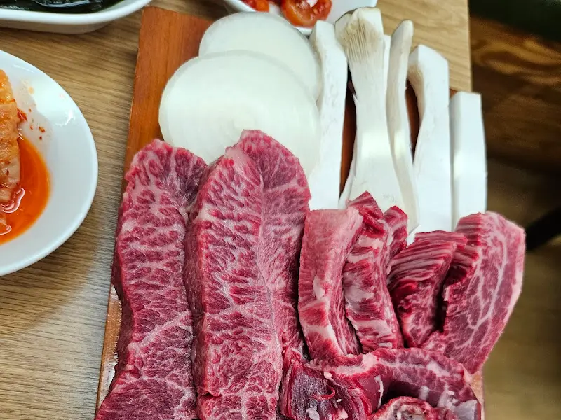 나무 도마 위에 올려진 한우 모듬. 붉은색과 흰색의 조화가 아름답다.