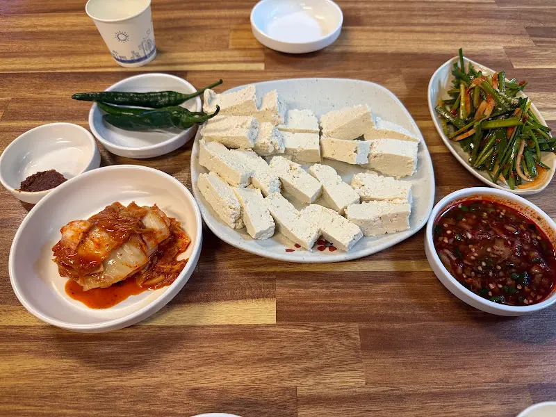 윤기가 흐르는 볶음김치와 깻잎 장아찌, 간장 양념과 함께 제공되는 촌두부