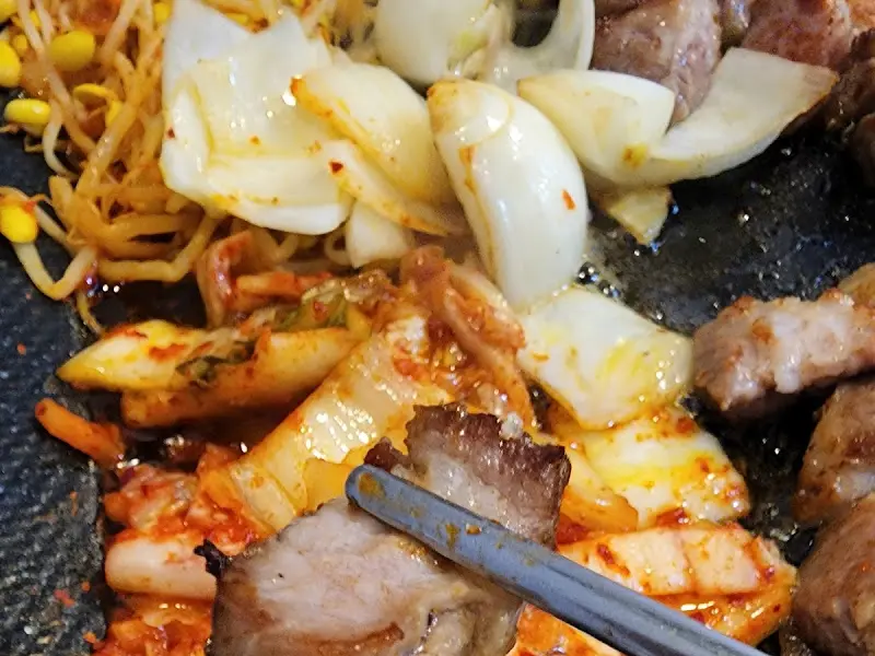 잘 구워진 삼겹살을 젓가락으로 집어 올리는 모습