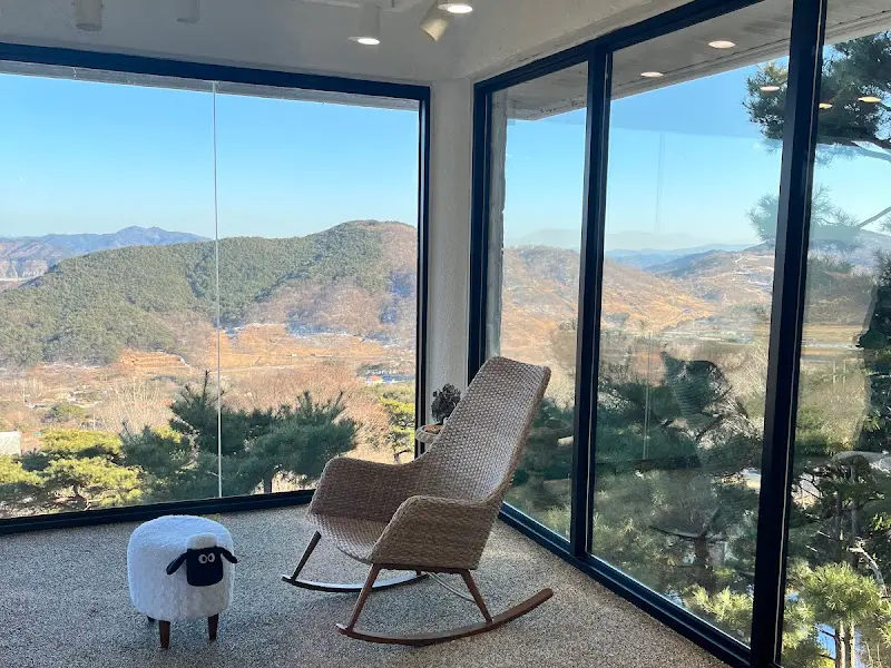 통창 옆 흔들의자와 양 인형