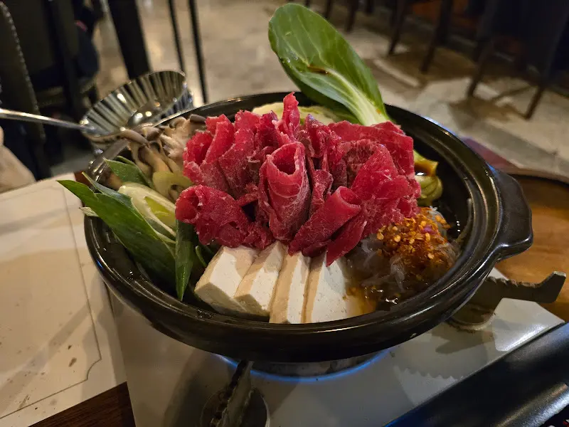 스키야키 냄비에 한우와 채소가 가득 담겨 보글보글 끓고 있는 모습