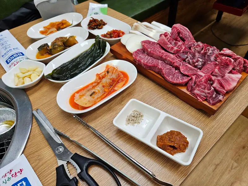 상에 차려진 한 상 차림. 정갈한 밑반찬과 신선한 고기가 인상적이다.