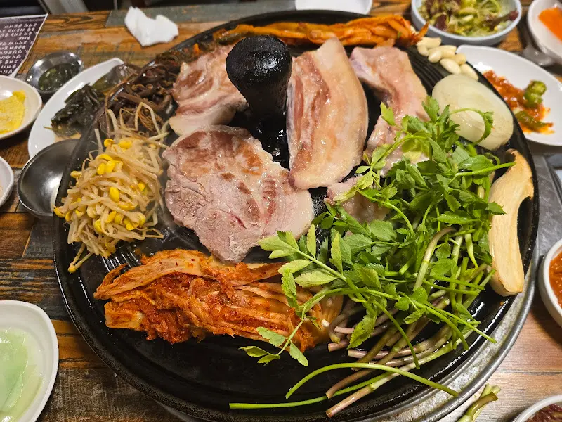 솥뚜껑 위에 푸짐하게 차려진 삼겹살 한 상