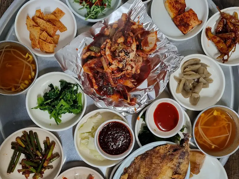 쟁반 가득 담긴 다양한 반찬들과 메인 요리인 오징어 두루치기