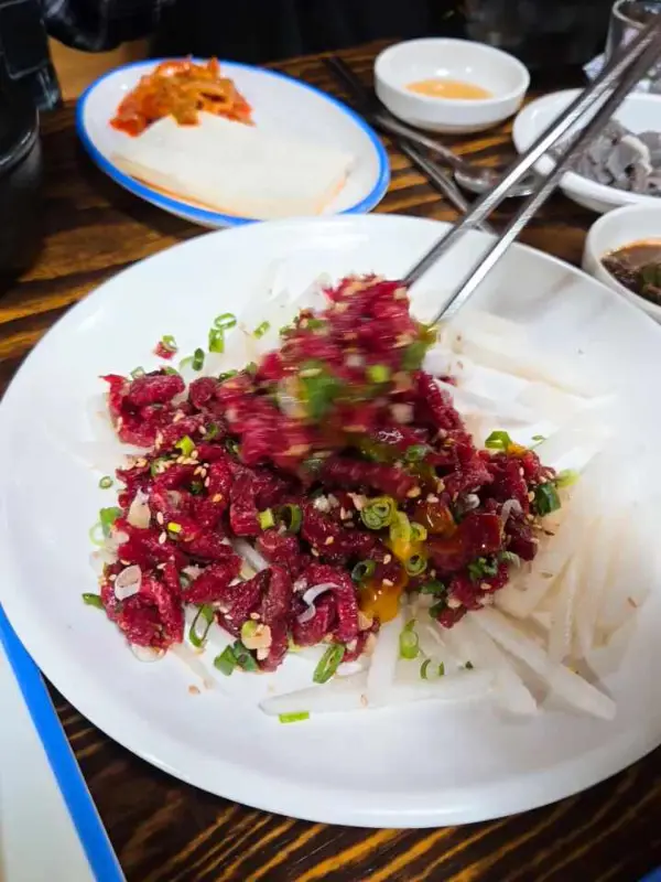 뭉티기를 젓가락으로 집어 올리는 모습