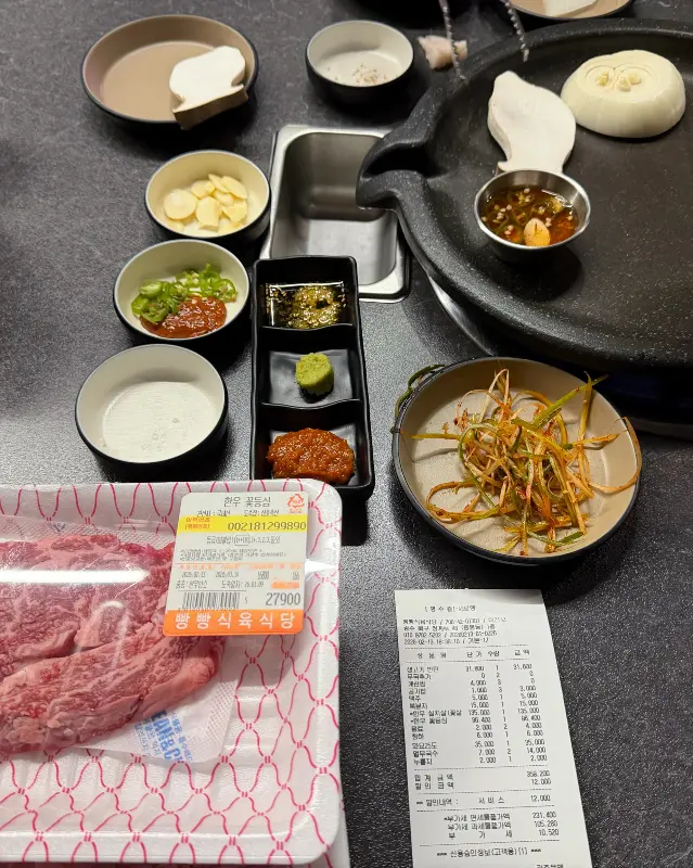 고기, 밑반찬, 영수증이 놓인 테이블