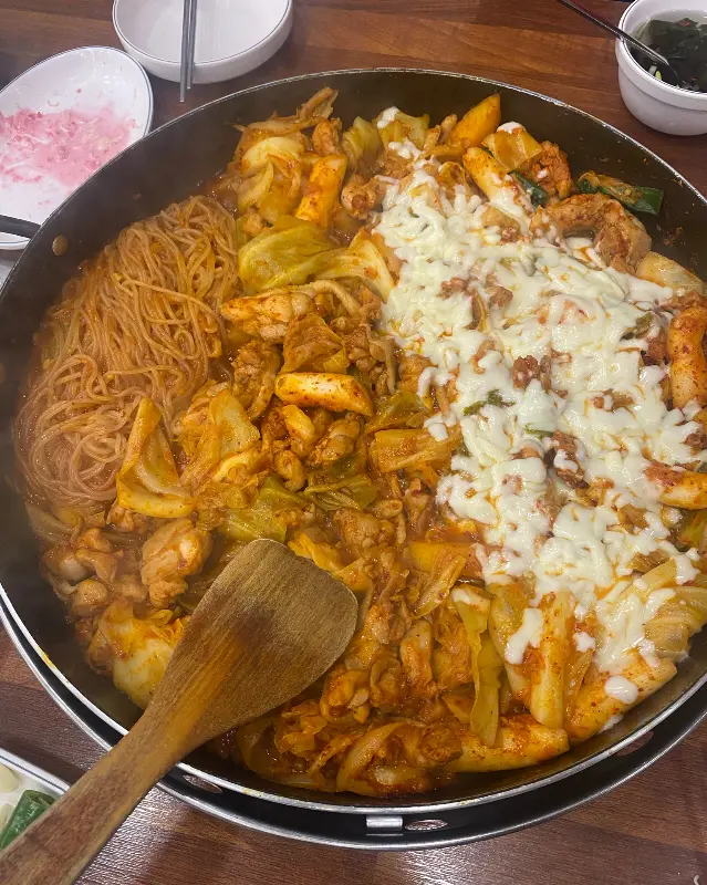닭갈비 철판에 쫄면과 치즈가 함께 올려져 있는 모습