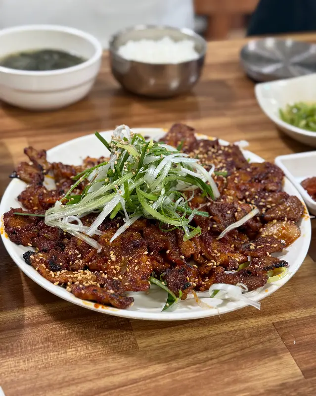 흑돼지 석쇠구이 위에 듬뿍 올려진 파와 깨