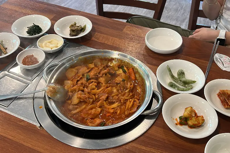 돼지 두루치기와 함께 다양한 밑반찬이 테이블 가득 차려져 있다.