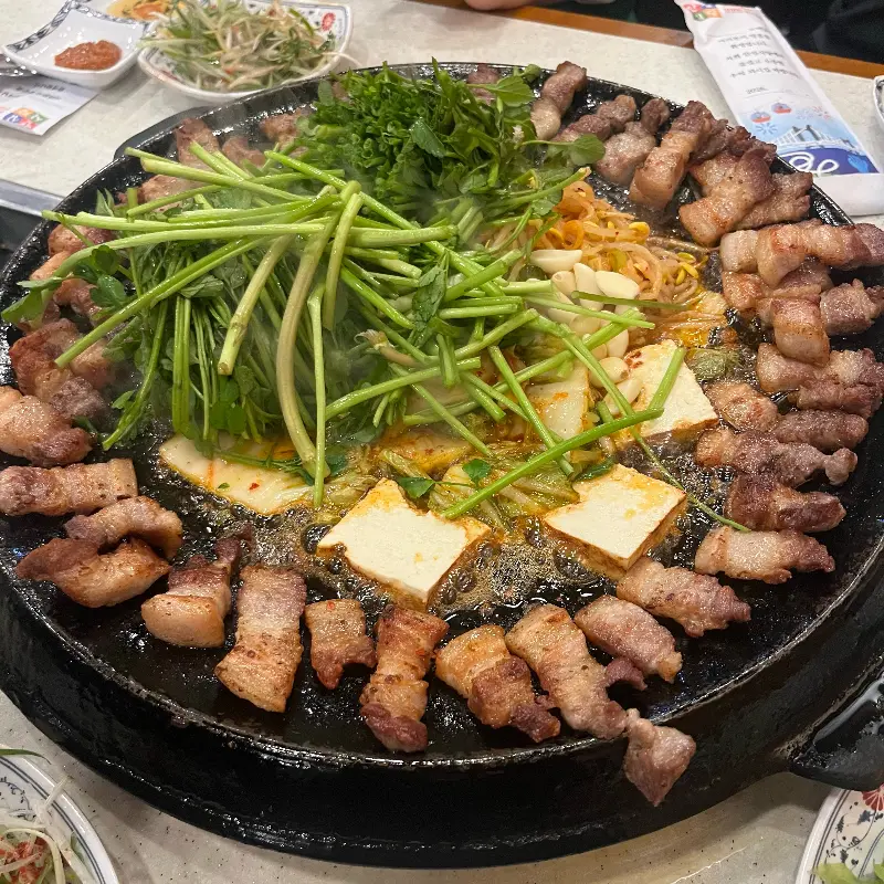 미나리, 김치, 콩나물과 함께 구워지는 삼겹살