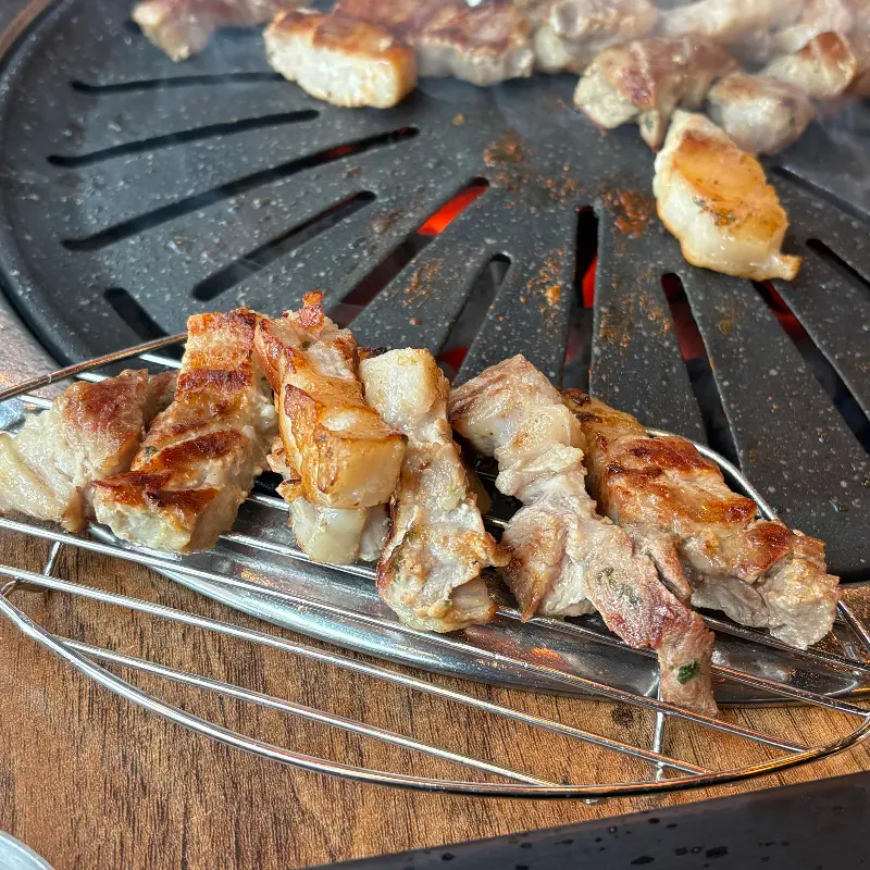 숯불 위에서 노릇하게 구워진 삼겹살