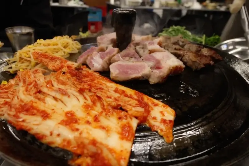 솥뚜껑에 구워지는 삼겹살과 김치