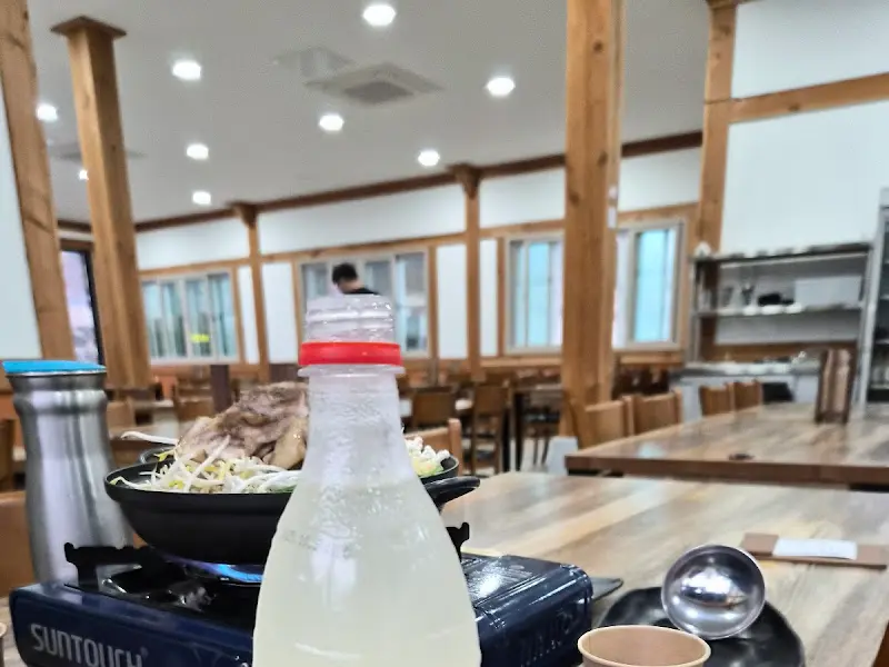 식탁 위에 놓인 막걸리 병과 전골 뚝배기