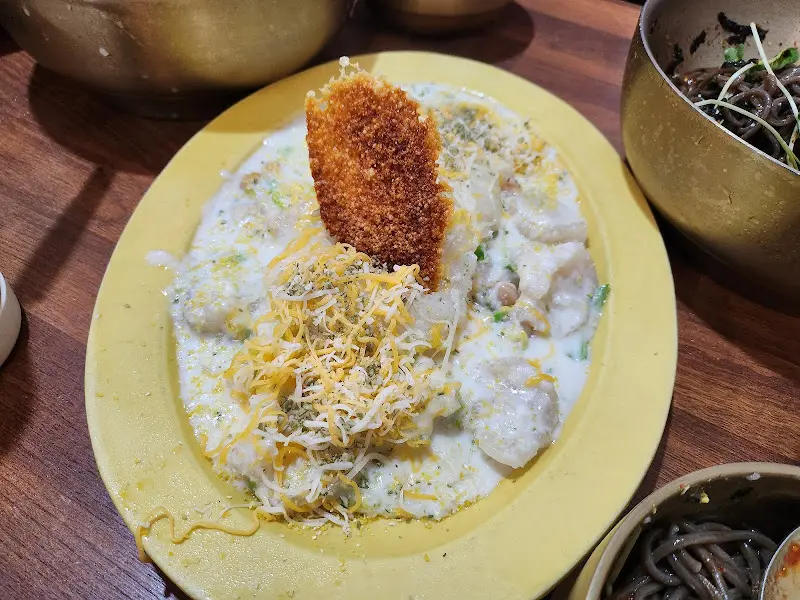 크림소스에 덮인 옹심이 위에 치즈칩이 올려진 크림 옹심이