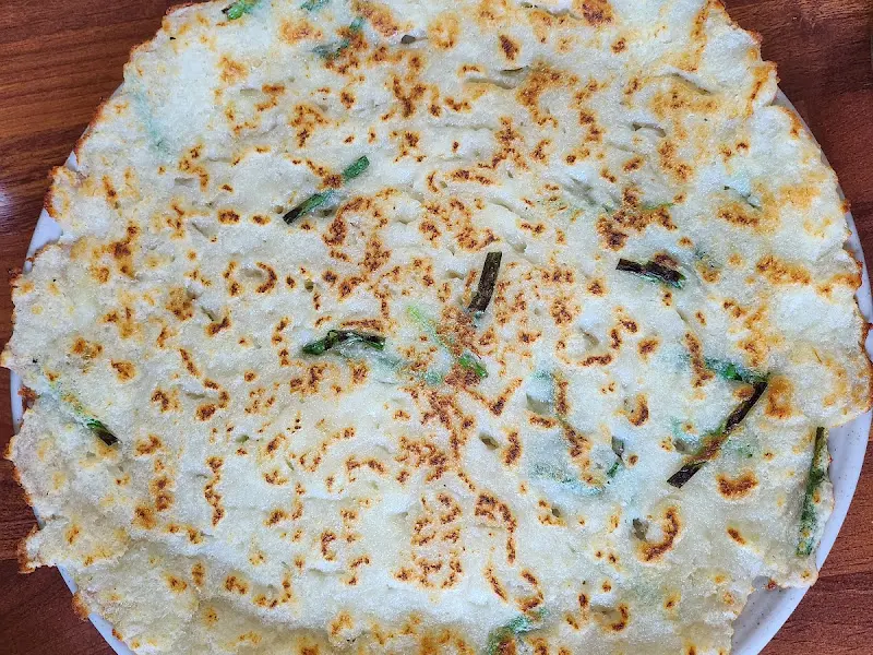 테이블 위에 놓인 감자전의 모습. 감자전 위에 젓가락이 놓여 있다.