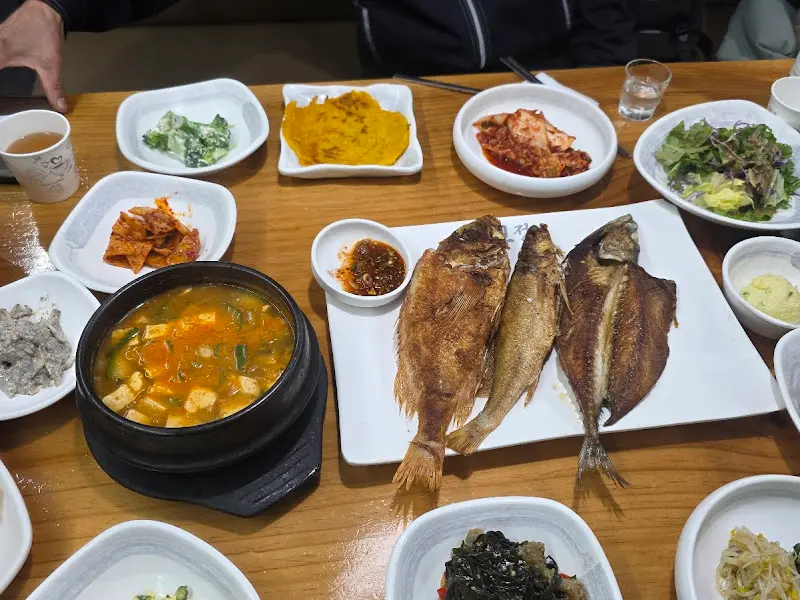 다양한 반찬과 생선구이, 된장찌개로 가득 찬 테이블