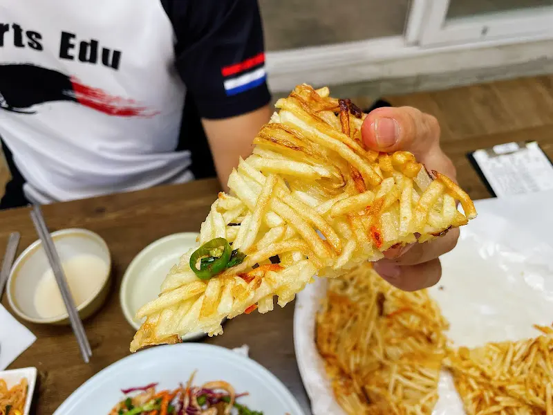 감자채전 한 조각을 들어 올리는 모습