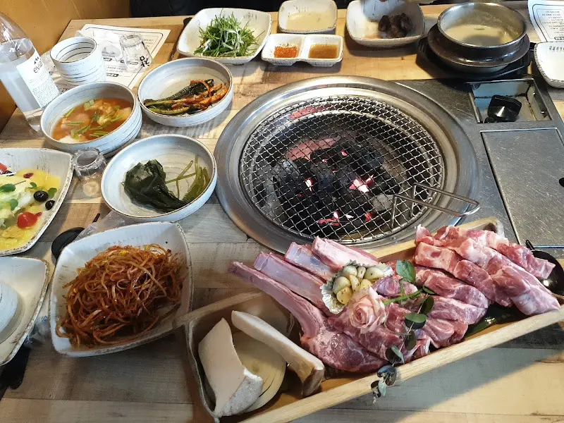 숯불 화로와 정갈하게 차려진 밑반찬, 그리고 꿀배갈비살